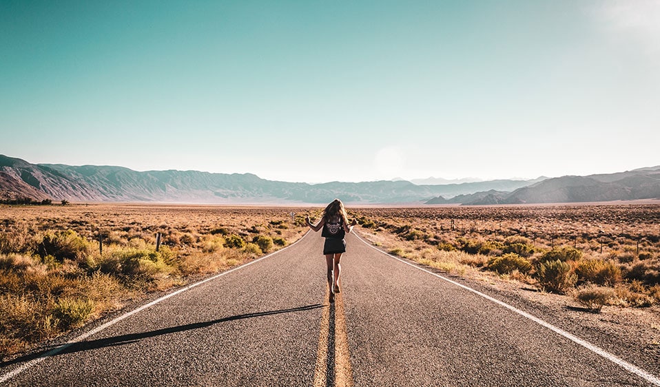 A woman walking down an empty road in California's desert.